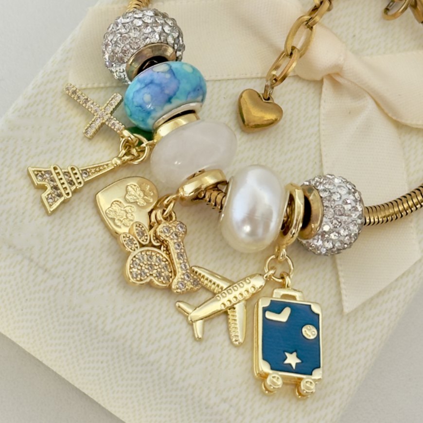 Pulsera dorada con cuenta azul, perla y charms de avión y maleta